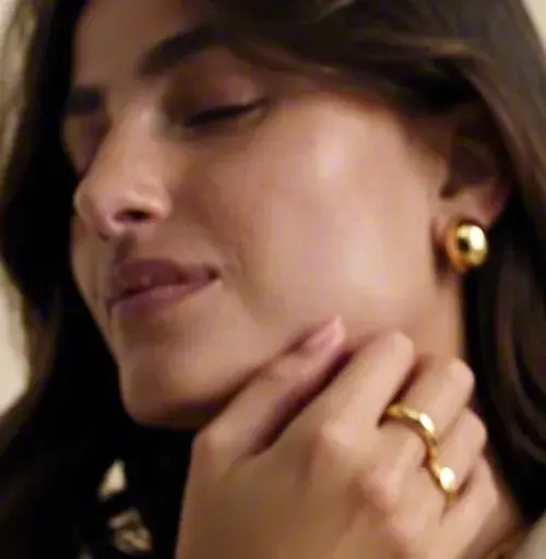 Mulher com brinco dourado, mão no pescoço