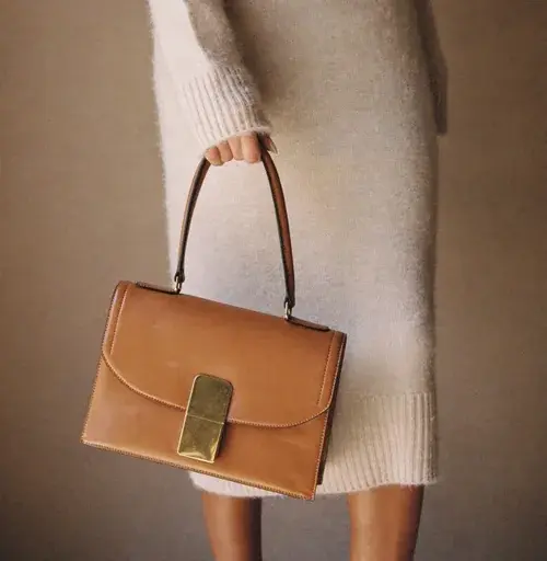 Modelo segurando uma bolsa caramelo