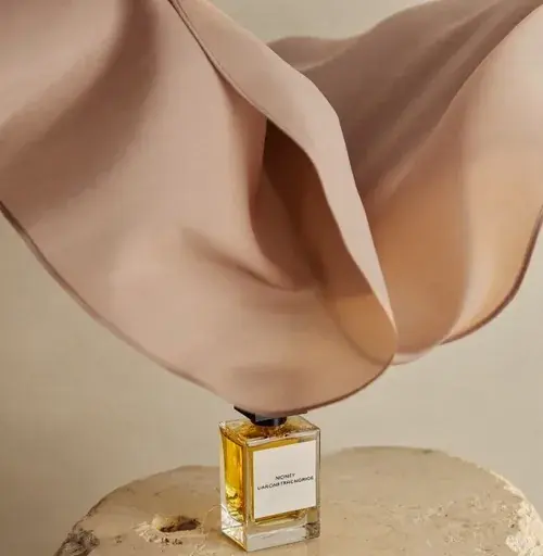 Frasco de perfume sob tecido em movimento