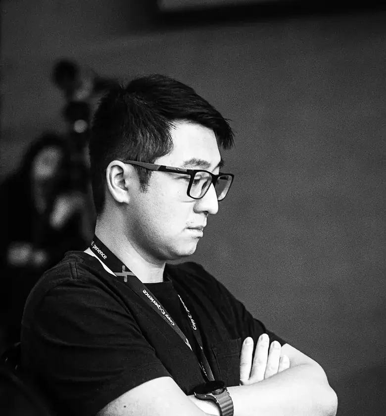 Kevin Chen, em preto e branco, de perfil e braços cruzados